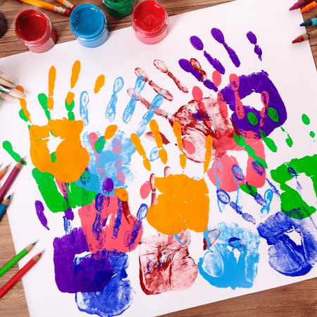 Een vel papier vol gekleurde handafdrukken van kinderen, met verf en potloden eromheen